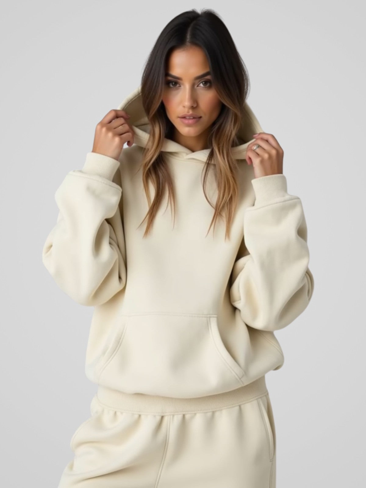 Woman wearing a cream oversized hoodie, standing and facing forward to show the fit and style.