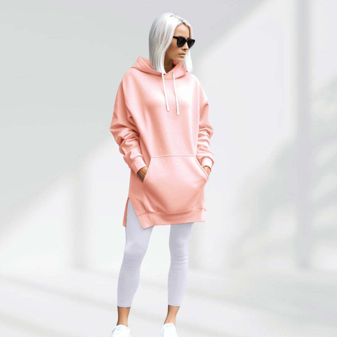 Woman wearing a light pink hoodie dress, standing and facing forward to show the fit and style.