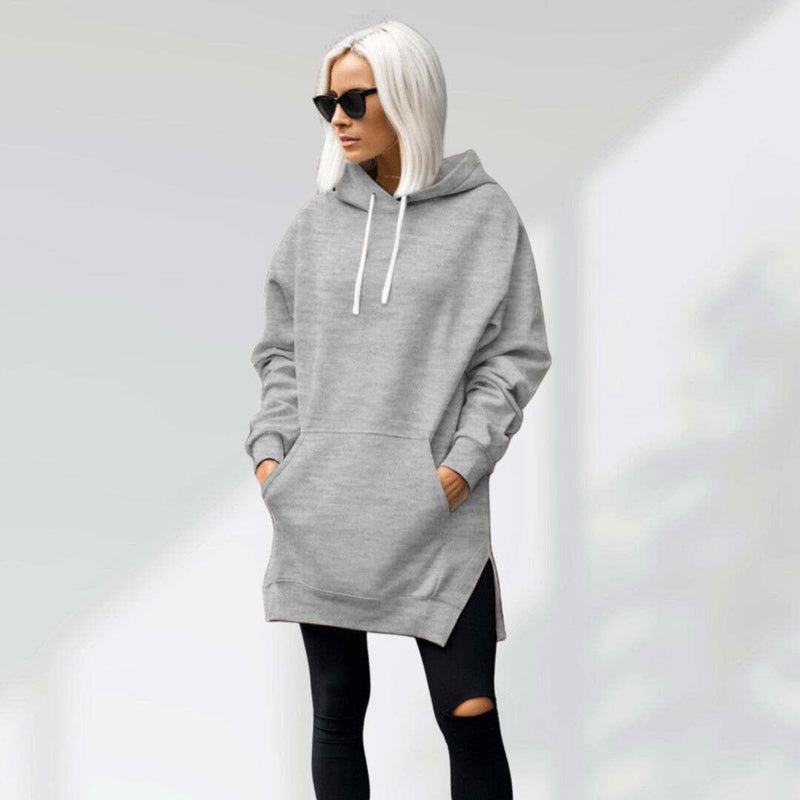Woman wearing a light gray hoodie dress, standing and facing forward to show the fit and style.